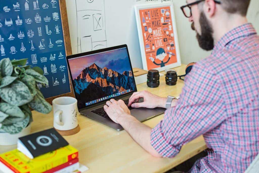 Man In A Checked Shirt Works On His Laptop